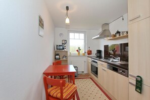 Una cocina compacta con una mesa de comedor, sillas, microondas, cafetera y un lavabo.