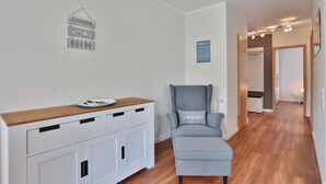 A modern room with a wooden desk, a grey armchair, and a small table with a plate.