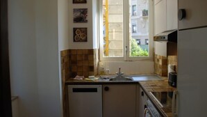 Eine kleine Küche mit Fenster, Fliesenrückwand und Geschirrspüler.