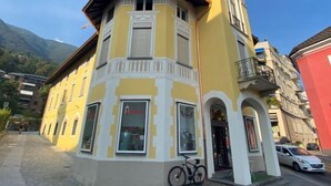 Ein Eckgebäude mit gelber Fassade, weißem Zierdekor und einem kleinen Balkon.