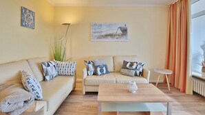 A living room with a beige sofa, a small round table, and a floor lamp.