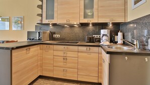 A compact kitchen with wooden cabinets, a built-in stove, a sink, and a coffee maker.