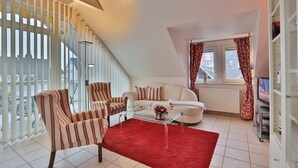 Een moderne woonkamer met een trap, een zithoek en een rood vloerkleed.