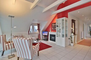 Uma sala de estar moderna com lareira, poltronas listradas, televisão de tela plana e uma parede em destaque vermelha.