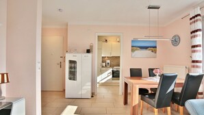 A modern kitchen with a refrigerator, a dining table with chairs, and a kitchen island. - Residenz Seeschwalbe Appartement 4 - Residenz Seeschwalbe (Scharbeutz)
