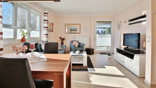 A modern living room with a dining area, a sofa, a TV, and a kitchen area. - Residenz Seeschwalbe Appartement 4 - Residenz Seeschwalbe (Scharbeutz)