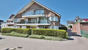 A multi-story residential building with balconies, a brick facade, and a paved driveway. - Seesternresidenz Apartment 15 - Seesternresidenz (Scharbeutz)