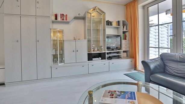 A living room with a glass coffee table, a leather sofa, a TV, and a bookshelf. - Seesternresidenz Apartment 15 - Seesternresidenz (Scharbeutz)