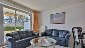 A living room with two black leather sofas, a glass coffee table, and a framed painting on the wall. - Seesternresidenz Apartment 15 - Seesternresidenz (Scharbeutz)