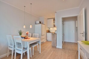 Une cuisine moderne avec des meubles blancs, un four encastré et un plan de travail en bois.