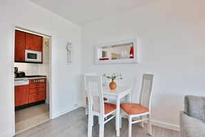 Et moderne køkken med mikrobølgeovn, brødrister og skabe, et spisebord med stole og et spejl over bordet.