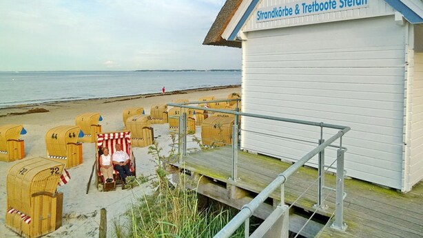 Um edifício à beira-mar com um letreiro que diz "Strandkörbe & Tretboote Stefan".