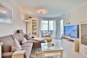 Una sala de estar moderna con un sofá, una mesa de centro, un televisor y un comedor con una mesa y sillas.