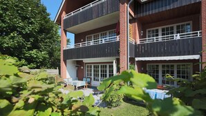 A two-story building with a balcony, a patio area with outdoor furniture, and a brick facade.