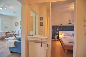 Ein modernes Hotelzimmer mit einem Bett, einem kleinen Hocker, einem Spiegel und einer Heizung.