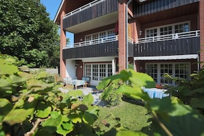 Un edificio de dos pisos con balcón y un patio.