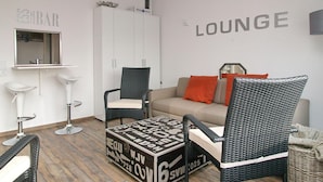 A modern lounge area with a sofa, two wicker chairs, a small table, and a cabinet. - Seetempel Apartment 42 - Seetempel (Scharbeutz)