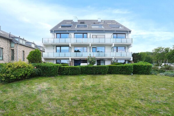 Un immeuble résidentiel à plusieurs étages, doté d’un toit plat, de grandes fenêtres et d’une pelouse bien entretenue.