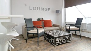 Un salon moderne comprenant un canapé, deux fauteuils, une table basse et une grande fenêtre.