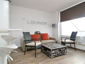 A modern lounge with a sofa, two chairs, a coffee table, and a large window. - Seetempel Apartment 42 - Seetempel (Scharbeutz)