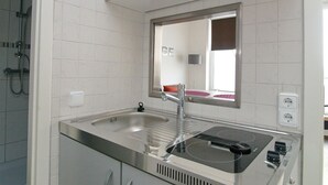 Une cuisine moderne dotée d’un évier en acier inoxydable, d’une plaque de cuisson intégrée et d’un miroir au-dessus de l’évier.