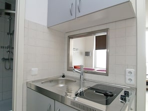 A modern kitchen with a stainless steel sink, a built-in stovetop, and a mirror above the sink. - Seetempel Apartment 42 - Seetempel (Scharbeutz)