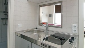 A modern kitchen with a stainless steel sink, a built-in stovetop, and a mirror above the sink. - Seetempel Apartment 42 - Seetempel (Scharbeutz)