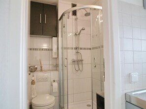 Een moderne badkamer met een douchecabine van glas, een toilet en een wastafel.