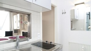 A modern kitchen with a stainless steel sink, a built-in stovetop, and a large mirror above the counter. - Seetempel Apartment 42 - Seetempel (Scharbeutz)