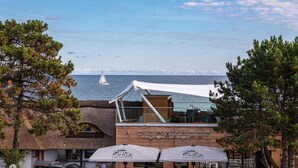 Een restaurant aan de kust met uitzicht op zee, met een houten gevel en terras met parasols.