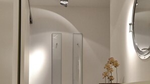 Een moderne badkamer met een glazen douchecabine, een wit wastafelmeubel met een spiegel en een decoratieve vaas op het meubel.