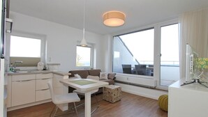 Een moderne, goed verlichte kamer met een keuken, eethoek en grote ramen met uitzicht.