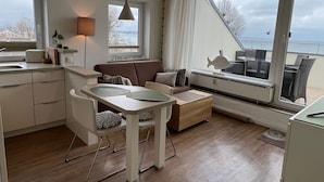 Een moderne keuken met een eethoek, een bank en uitzicht op zee.