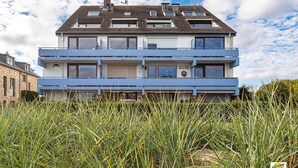 Een woongebouw met twee verdiepingen, een plat dak en meerdere ramen, met een zichtbaar huisnummer.