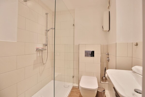 Un baño moderno con cabina de ducha de vidrio, un inodoro y un lavabo con espejo.