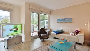 Una sala de estar moderna con televisor, sofá, mesa de centro y una silla.
