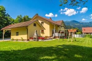 A yellow house with a red-tiled roof, a patio with outdoor seating, and a swing set. - Villa Cujez with Pool & Sauna, Rečica ob Savinji, Slovenia (Rečica ob Savinji)