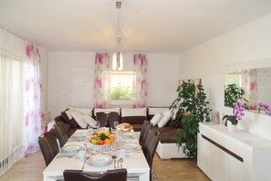 A dining area with a table set for four, surrounded by sofas, and a potted plant on the right. - Villa Cujez with Pool & Sauna, Rečica ob Savinji, Slovenia (Rečica ob Savinji)