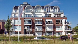 A multi-story residential building with balconies, large windows, and a brick facade. - Beach villa apartment 6 - Beach villa (Scharbeutz)