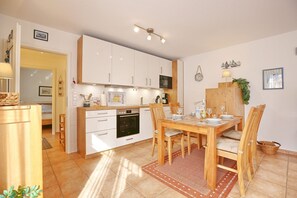 Una cucina moderna con mobili bianchi, un tavolo da pranzo in legno e un forno a incasso.