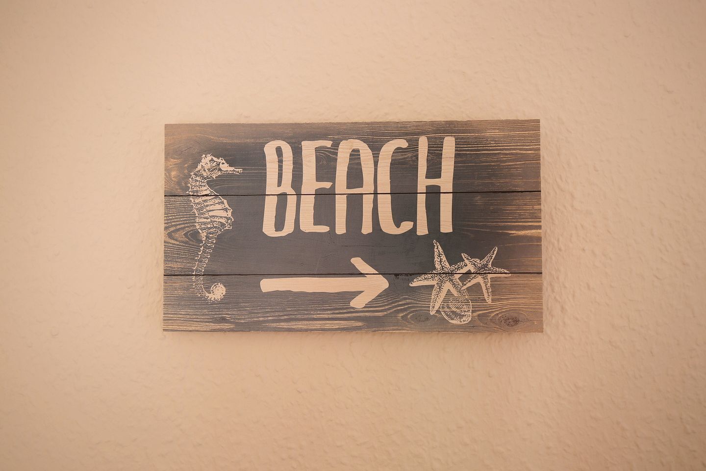 A wooden sign with the word "BEACH" and a starfish, indicating a direction to the beach.