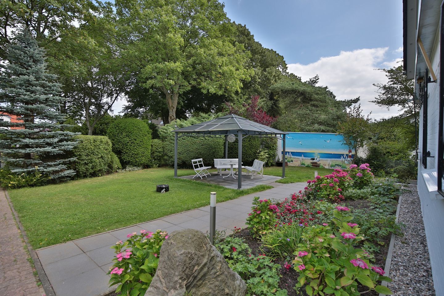 Ein Garten mit einem Pavillon, Sitzgelegenheiten und einem Weg.