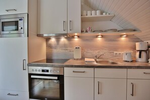 A modern kitchen with a built-in oven, microwave, and a coffee maker.