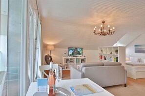 Una sala de estar moderna con televisor, sofá y muebles blancos.