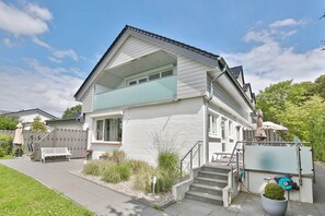 A two-story house with a balcony, a front porch, and a small garden area.