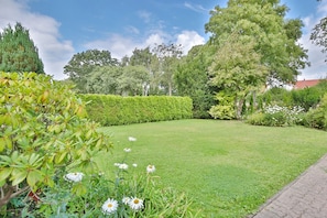A well-maintained garden with a lawn, hedges, and flowering plants.