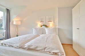 Ein ordentlich eingerichtetes Schlafzimmer mit Bett, Nachttischlampen und Kleiderschrank.