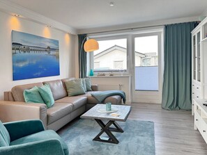 A modern living room with a beige sofa, teal armchairs, a coffee table, and a large window with curtains. - Apartment house Linda-Lu Apartment 9 - Apartment house Linda-Lu (Scharbeutz)