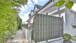 Zona residencial con entrada porticada, un sendero y una planta en maceta.