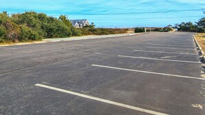 A large, empty parking lot with clearly marked parking spaces and a building in the background. - Goldenberg - 🏄Enjoy Spectacular Views from this 4 BR Oceanfront Home🏄 (Southern Shores)